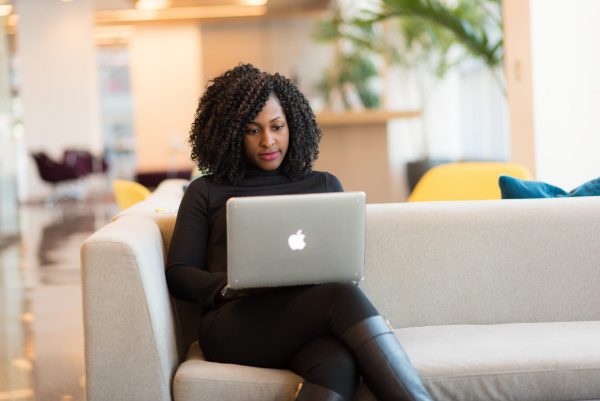 Mulher sentada em sofá com notebook no colo